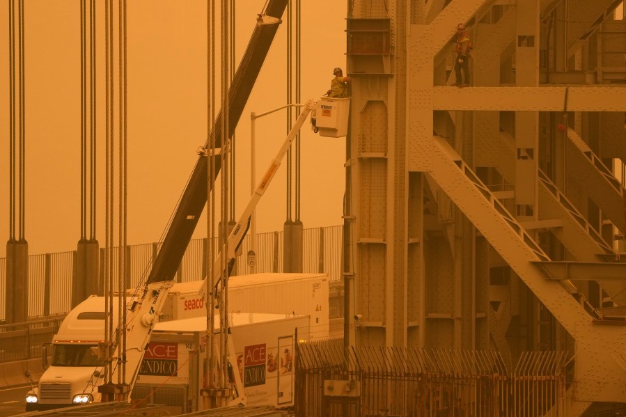 File - Workmen tend to the George Washington Bridge, as seen from Fort Lee, N.J., as haze from wildfires in Canada settles over the area on Wednesday, June 7, 2023. The haze from the wildfires is taking its toll on outdoor workers along the Eastern U.S. who carried on with their jobs even as dystopian orange skies forced the cancelation of sports events, school field trips and Broadway plays. (AP Photo/Seth Wenig, File)