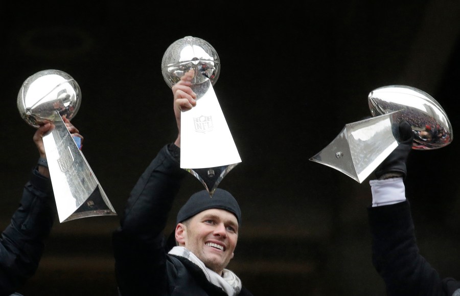 FILE - Then-New England Patriots quarterback Tom Brady holds a Super Bowl trophy, between others the team previously had won, during a rally in Boston to celebrate the team's 34-28 win over the Atlanta Falcons in the NFL Super Bowl 51 football game in Houston, Feb. 7, 2017. The seven-time Super Bowl champion is enjoying retirement while staying busy. He’s preparing for his new 2024 broadcasting gig at Fox Sports, is set to become a minority owner of the Las Vegas Raiders, and is focusing on his apparel and wellness brands. (AP Photo/Elise Amendola, File)