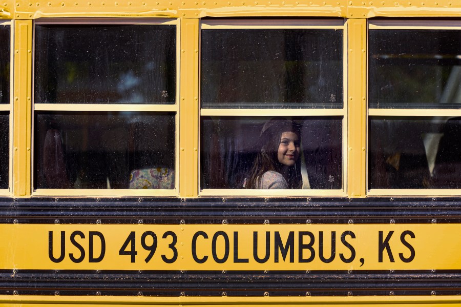 Third-grader Lucy Perry waits on a bus after classes at Highland Elementary School in Columbus, Kan., on Monday, Oct. 17, 2022. Third graders in the tiny 900-student Columbus school district have fought to catch up on reading in the wake of COVID-19 disruptions. (AP Photo/Charlie Riedel)