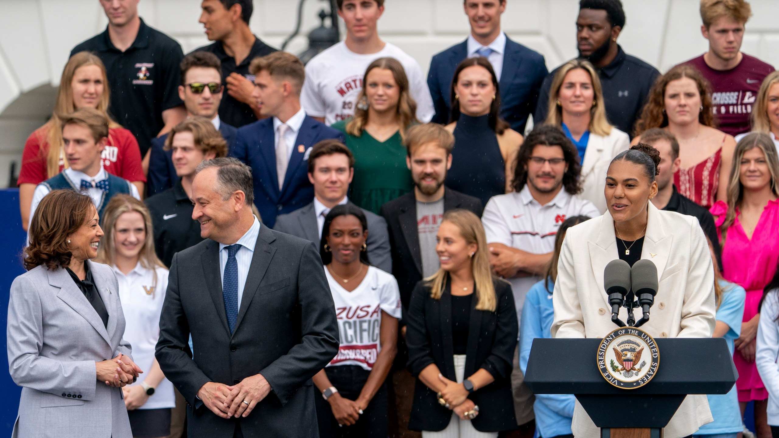 University of Texas at Austin volleyball player Logan Eggleston, right, accompanied by Vice President Kamala Harris, left, and Doug Emhoff, husband of Harris, second from left, speaks as the women's and men's NCAA Champion teams from the 2022-2023 season are celebrated during College Athlete Day on the South Lawn of the White House, Monday, June 12, 2023, in Washington. (AP Photo/Andrew Harnik)