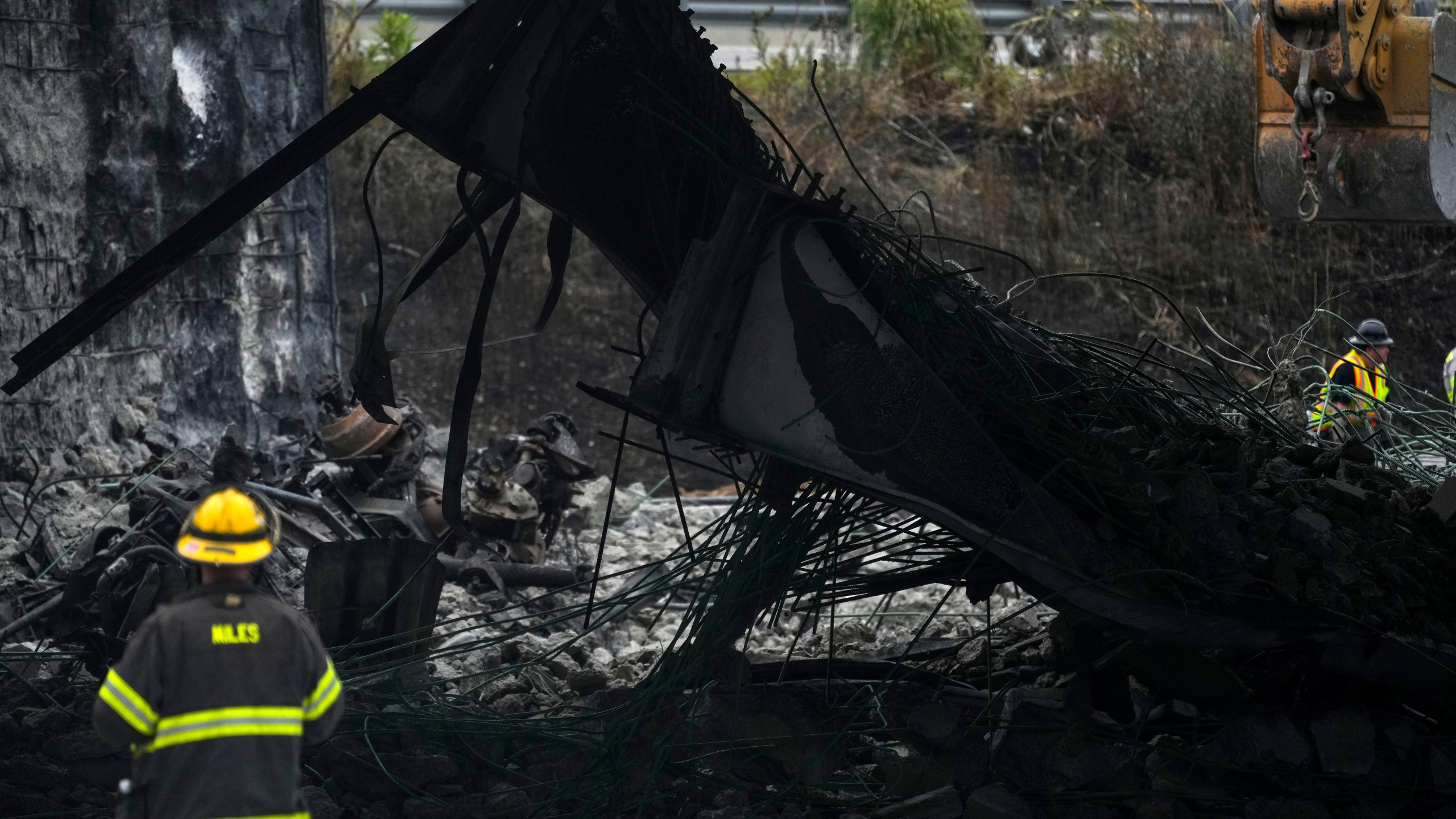 A firefighter views the aftermath of an elevated section of Interstate 95 that collapsed, in Philadelphia, Monday, June 12, 2023. Drivers began longer commutes after section of I-95 collapse a day earlier following damage caused by a tanker truck carrying flammable cargo catching fire. (AP Photo/Matt Rourke)