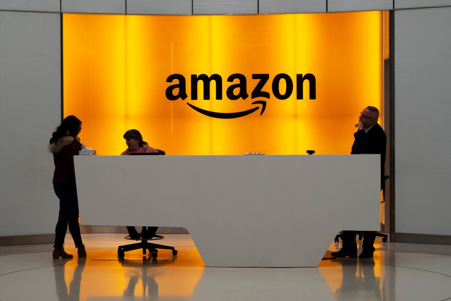 FILE - In this Feb. 14, 2019, file photo people stand in the lobby for Amazon offices in New York. Amazon is kicking off its annual security-focused cloud computing conference on Tuesday amid a slowdown in its profitable cloud business Amazon Web Services, or AWS. (AP Photo/Mark Lennihan, File)