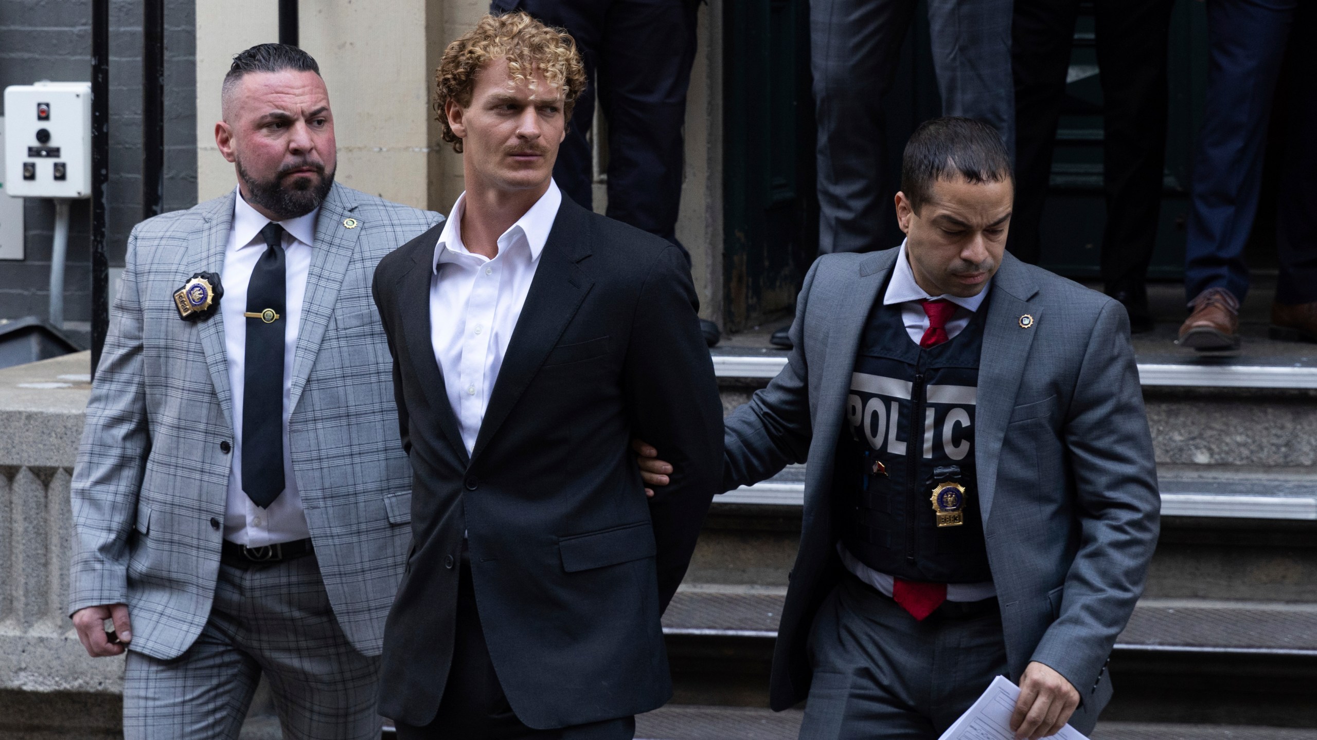 FILE - Daniel Penny, center, is walked by New York Police Department detectives out of the 5th Precinct, May 12, 2023, in New York. Penny, the man charged with manslaughter for putting an agitated New York City subway rider in a fatal chokehold, has been indicted by a grand jury, an expected procedural step that will allow the criminal case to continue. (AP Photo/Jeenah Moon, File)