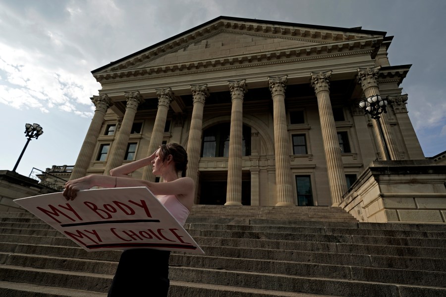 FILE - Zoe Schell, from Topeka, Kan., stands on the steps of the Kansas Statehouse during a rally to protest the Supreme Court's ruling on abortion, June 24, 2022, in Topeka. Abortion providers sued Kansas on Tuesday, June 6, 2023, challenging a new law requiring them to tell patients that an abortion medication can be stopped but also existing restrictions that include a decades-old requirement that patients wait 24 hours to terminate their pregnancies. (AP Photo/Charlie Riedel, File)