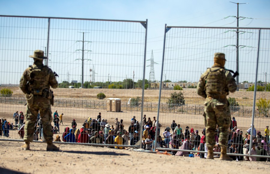 FILE - Migrants wait in line adjacent to the border fence under the watch of the Texas National Guard to enter into El Paso, Texas, Wednesday, May 10, 2023. U.S. authorities say an 8-year-old girl died Wednesday, May 17, in Border Patrol custody, a rare occurrence that comes as the agency struggles with overcrowding. The Border Patrol had 28,717 people in custody on May 10, the day before pandemic-related asylum restrictions expired, which was double from two weeks earlier, according to a court filing. (AP Photo/Andres Leighton, File)