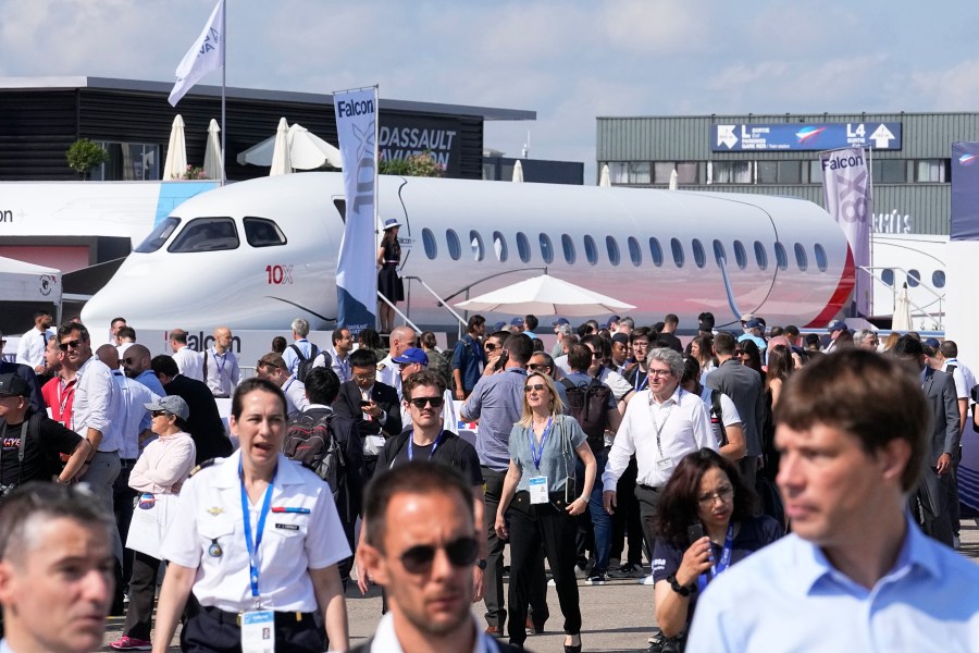 FILE - Visitors walk by a Falcon 10X prototype by the French manufacturer Dassault Aviation, at the Paris Air Show, Wednesday, June 21, 2023 in Le Bourget, north of Paris. Airlines are facing increasing pressure to cut their climate-changing emissions. That made sustainable aviation fuel a hot topic this week at the Paris Air Show, a major industry event. Sustainable fuel made from food waste or plant material is aviation's best hope for reducing emissions in the next couple of decades. (AP Photo/Michel Euler, File)