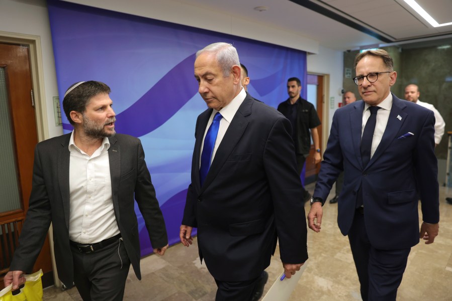 Israeli Prime Minister Benjamin Netanyahu, center, talks with Finance Minister Bezalel Smotrich, left, during the weekly cabinet meeting in the prime minister's office in Jerusalem, Sunday, June 25, 2023.(Abir Sultan/Pool Photo via AP)