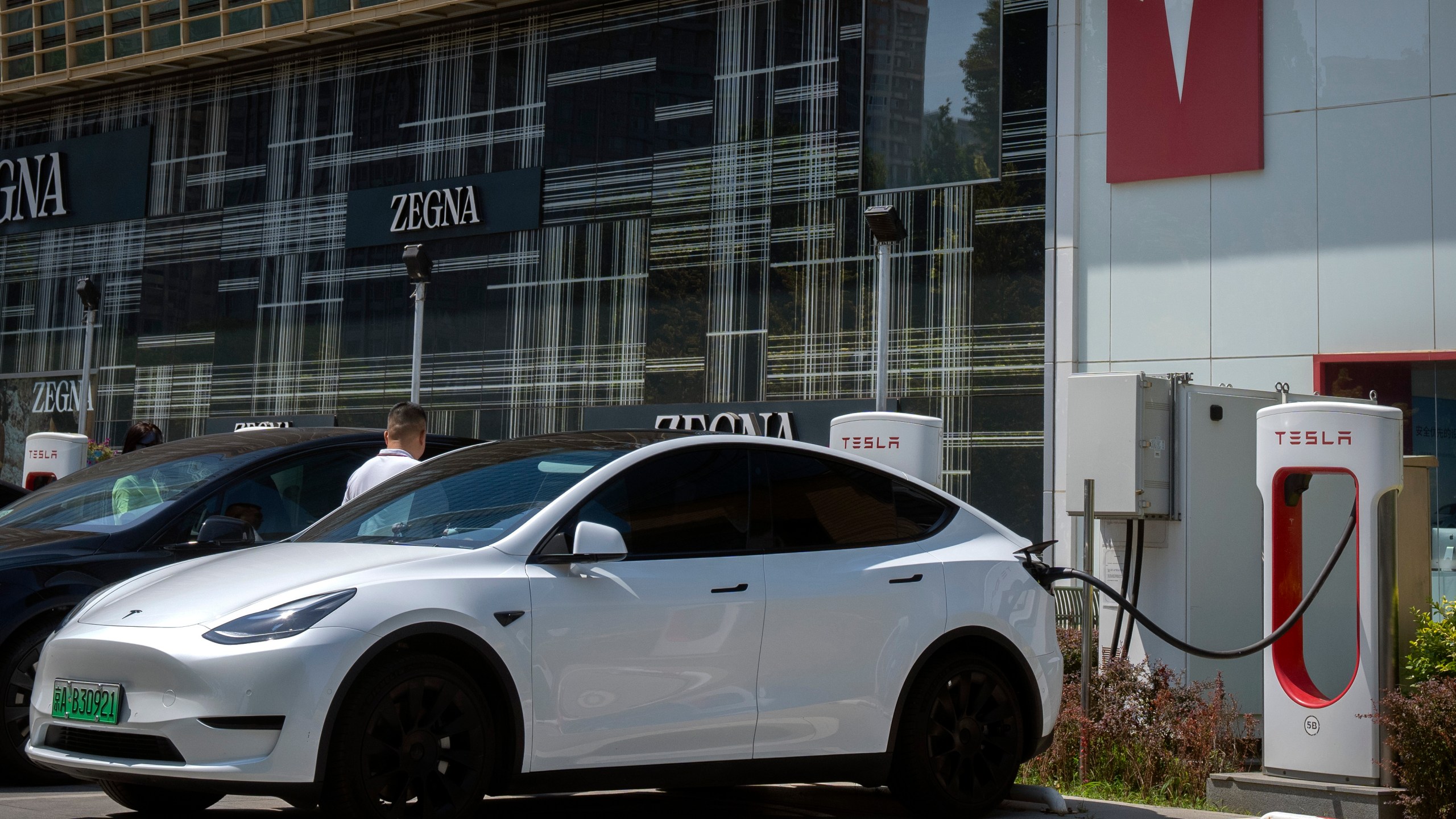 A driver gets into his car at an electric vehicle charging station outside of a Tesla dealership in Beijing, Saturday, June 24, 2023. Threatened by possible shortages of lithium for electric car batteries, automakers are racing to lock in supplies of the once-obscure "white gold" in a politically and environmentally fraught competition from China to Nevada to Chile. (AP Photo/Mark Schiefelbein)