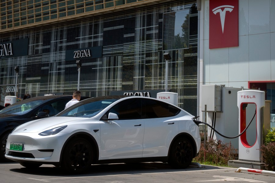 A driver gets into his car at an electric vehicle charging station outside of a Tesla dealership in Beijing, Saturday, June 24, 2023. Threatened by possible shortages of lithium for electric car batteries, automakers are racing to lock in supplies of the once-obscure "white gold" in a politically and environmentally fraught competition from China to Nevada to Chile. (AP Photo/Mark Schiefelbein)