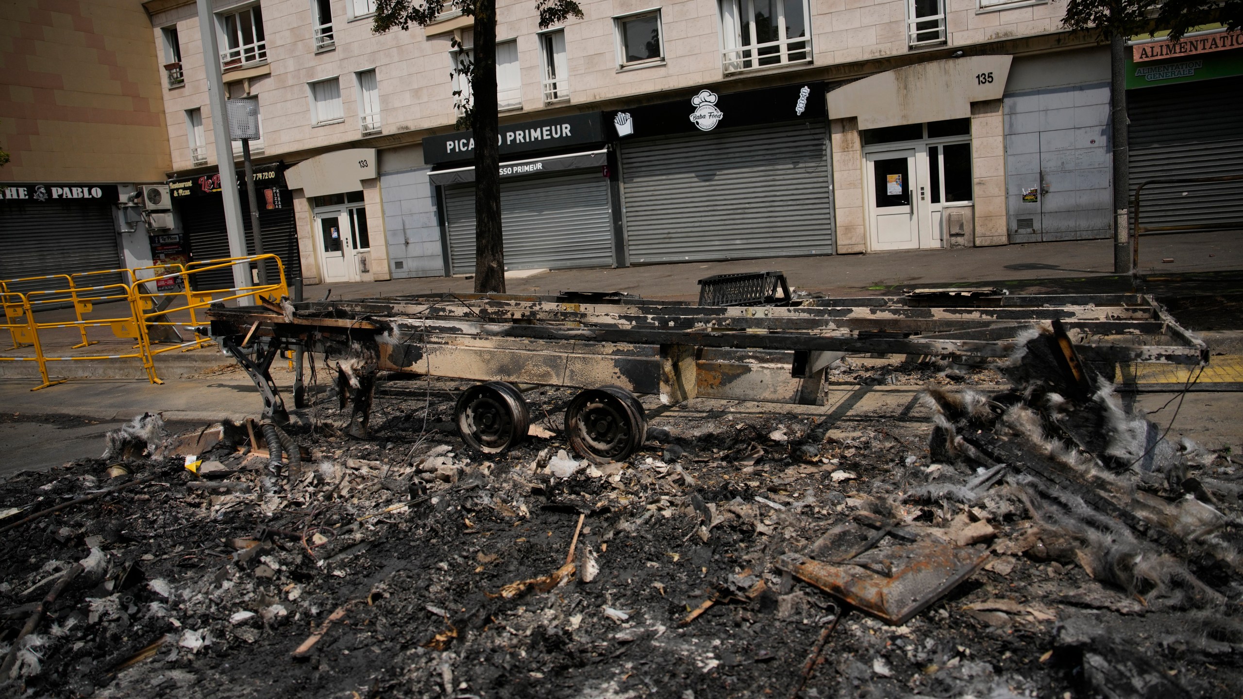 A charred vehicle is pictured Wednesday, June 28, 2023 in Nanterre, outside Paris. France's government announced heightened police presence around Paris and other big cities and called for calm after scattered violence erupted over the death of a 17-year-old delivery driver who was shot and killed Tuesday June 27, 2023 during a police check. (AP Photo/Lewis Joly)