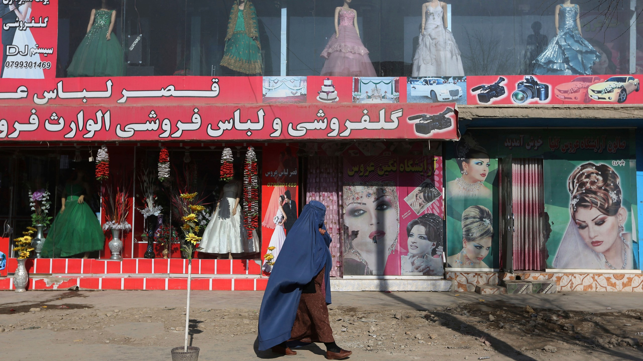 FILE - A woman walks past a beauty salon and dress shop in Kabul, Afghanistan, Sunday, Dec. 13, 2015. A spokesman at Afghanistan's Vice and Virtue Ministry said Tuesday, July 4, 2023, the Taliban are banning women's beauty salons. (AP Photo/Rahmat Gul, File)