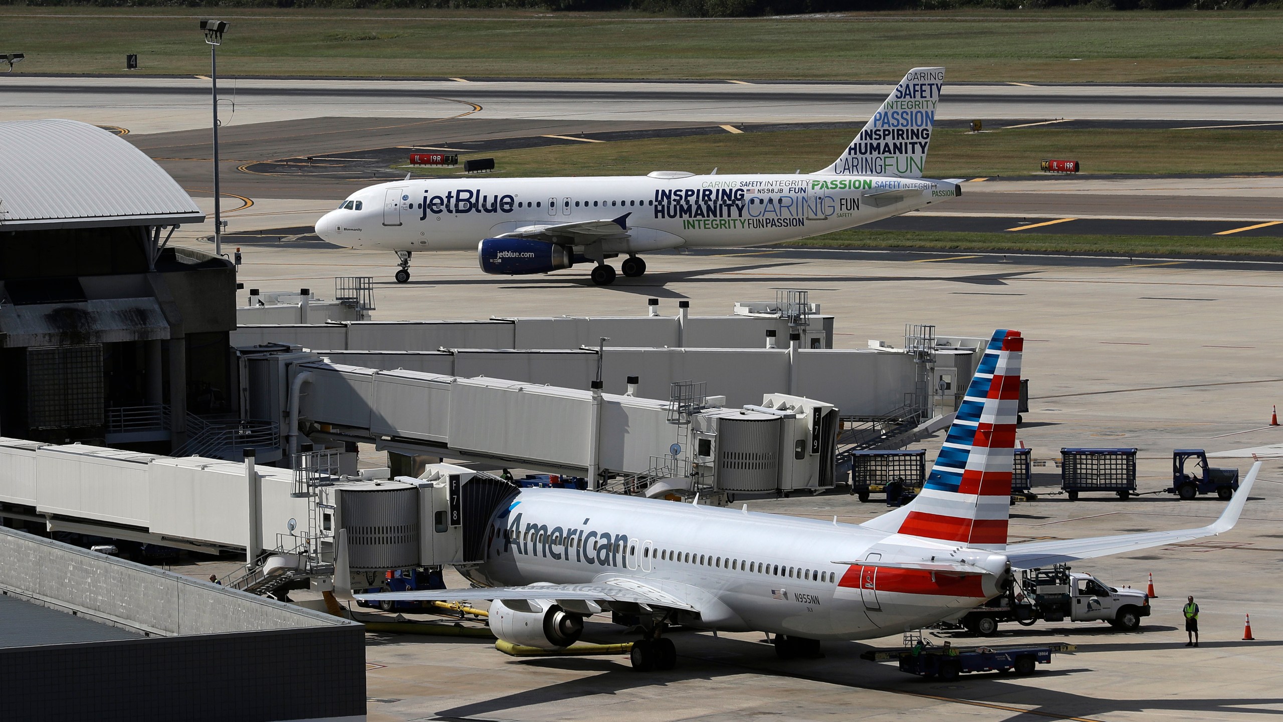 FILE - A JetBlue Airbus A320 taxis to a gate after landing, Oct. 26, 2016, as an American Airlines jet is seen parked at its gate at Tampa International Airport in Tampa, Fla. JetBlue on Wednesday, July 5, 2023, said it won't appeal a judge's ruling against its partnership with American Airlines, effectively dropping the deal in an effort to salvage its purchase of Spirit Airlines. (AP Photo/Chris O'Meara, File)