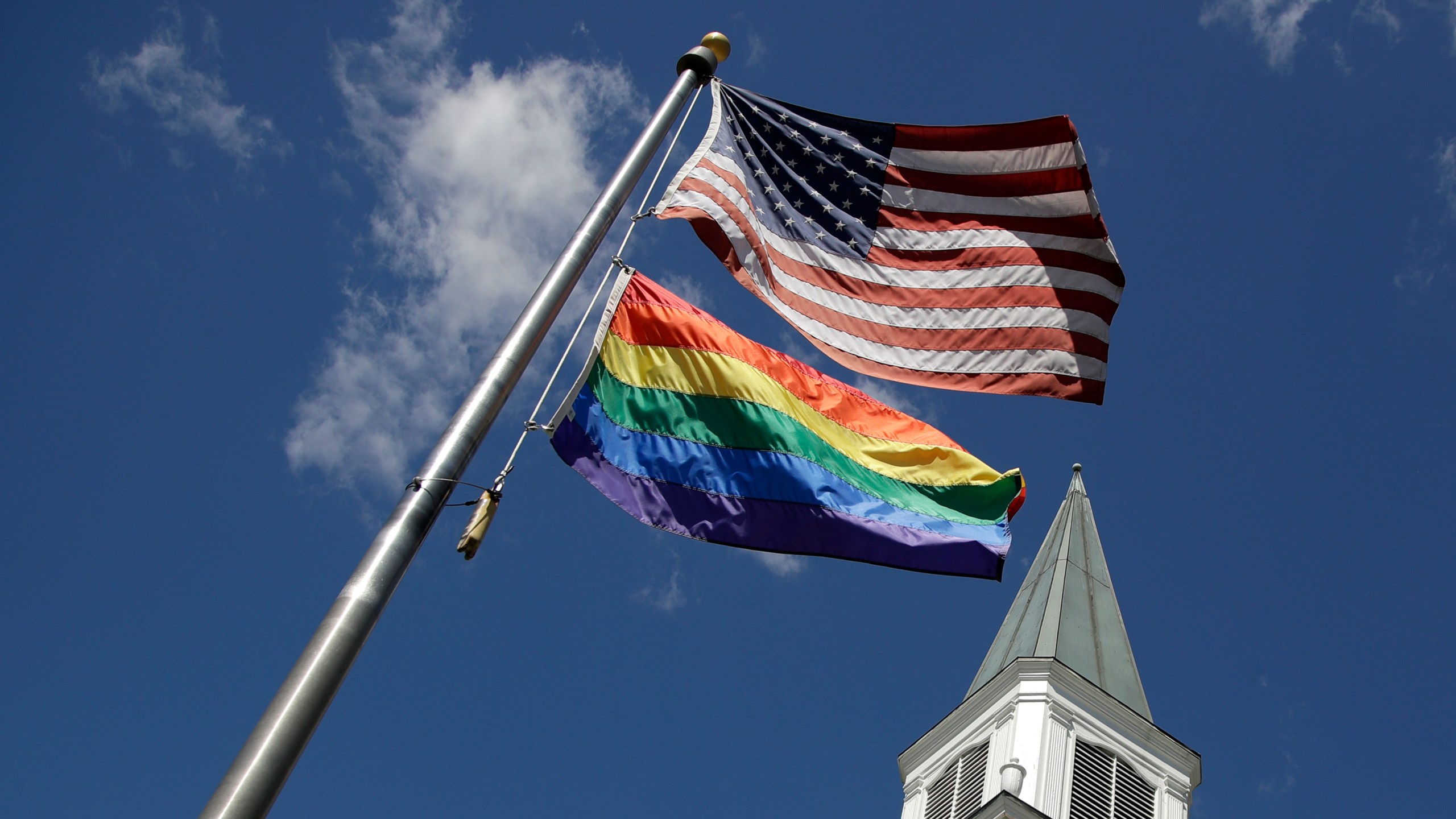 FILE - A gay Pride rainbow flag flies with the U.S. flag in front of the Asbury United Methodist Church in Prairie Village, Kan., on Friday, April 19, 2019. As of June 2023, more than 6,000 United Methodist congregations — a fifth of the U.S. total — have now received permission to leave the denomination amid a schism over theology and the role of LGBTQ people in the nation's second-largest Protestant denomination. (AP Photo/Charlie Riedel, File)