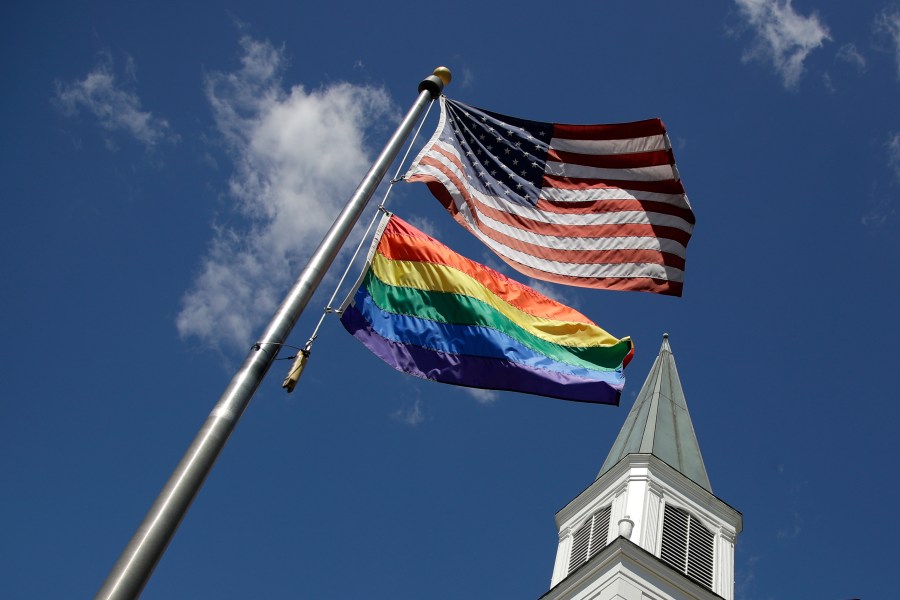 FILE - A gay Pride rainbow flag flies with the U.S. flag in front of the Asbury United Methodist Church in Prairie Village, Kan., on Friday, April 19, 2019. As of June 2023, more than 6,000 United Methodist congregations — a fifth of the U.S. total — have now received permission to leave the denomination amid a schism over theology and the role of LGBTQ people in the nation's second-largest Protestant denomination. (AP Photo/Charlie Riedel, File)