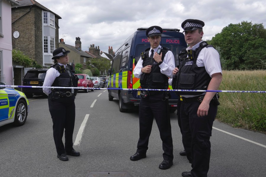 Police officers set up cordon line as a car crashed into a primary school building in Wimbledon, London, Thursday, July 6, 2023. London police say a girl died when an SUV crashed into an elementary school on a very narrow road in the Wimbledon district of southwest London. The Metropolitan Police said Thursday that there have been further injuries but did not provide details of how many. (AP Photo/Kin Cheung)