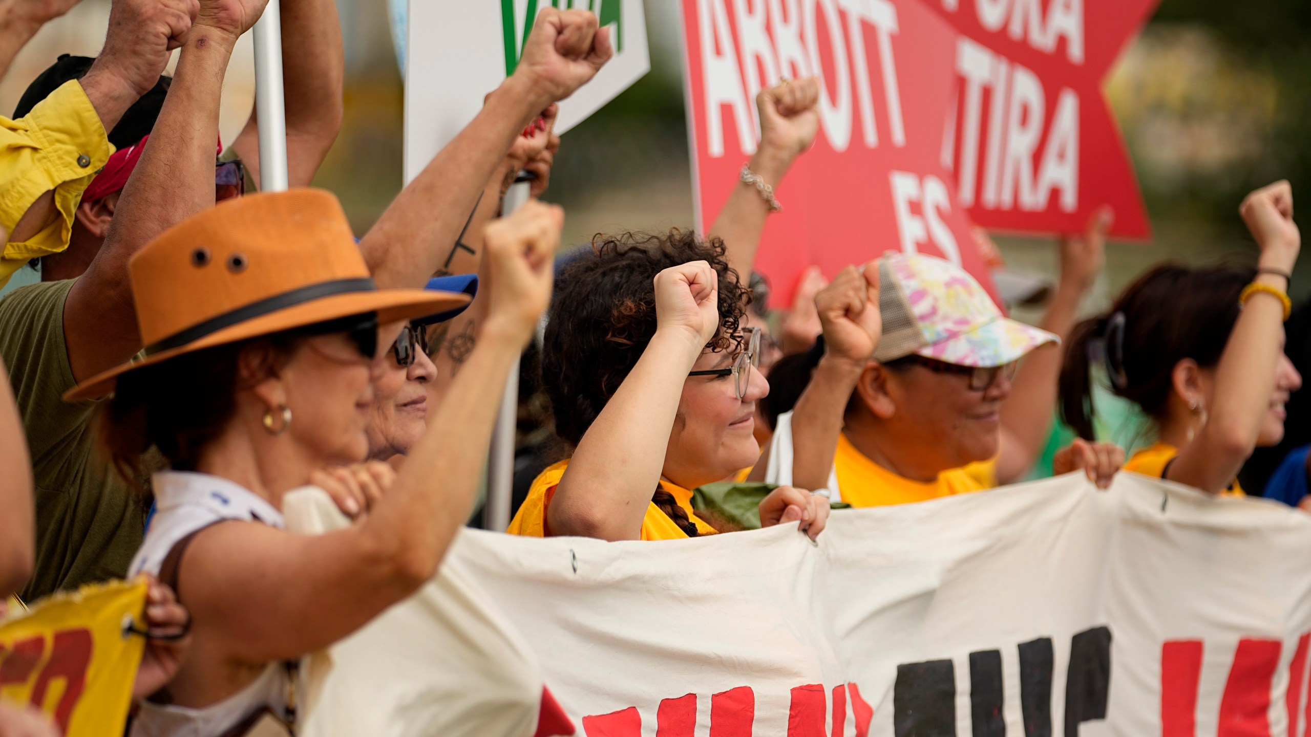 A group holds signs as they protest against buoys that are set to be deployed in the Rio Grande, Friday, July 7, 2023, in Eagle Pass, Texas, where border crossings continue to place stress on local resources. Advocates have raised concern that the barriers may have an adverse environmental impact. (AP Photo/Eric Gay)