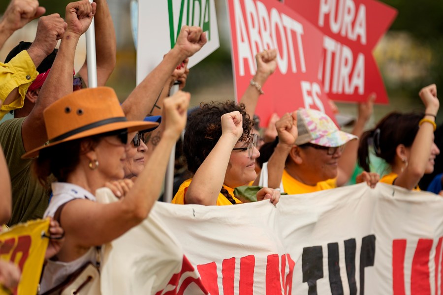 A group holds signs as they protest against buoys that are set to be deployed in the Rio Grande, Friday, July 7, 2023, in Eagle Pass, Texas, where border crossings continue to place stress on local resources. Advocates have raised concern that the barriers may have an adverse environmental impact. (AP Photo/Eric Gay)