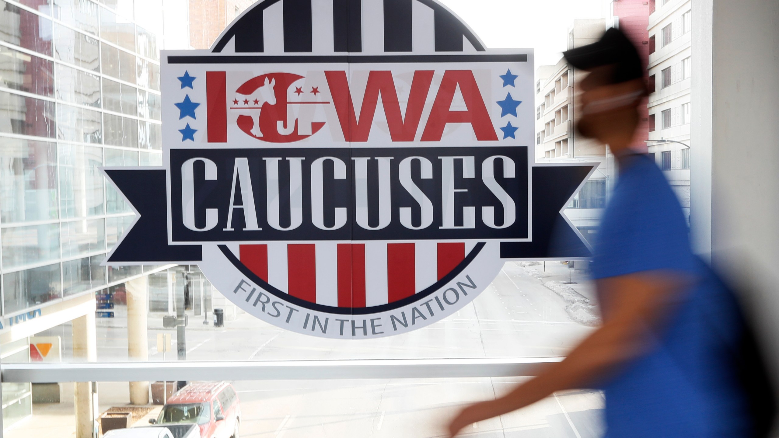 FILE - A pedestrian walks past a sign for the Iowa Caucuses on a downtown skywalk, in Des Moines, Iowa, on Feb. 4, 2020. Iowa Republicans have scheduled the party’s presidential nominating caucuses for Jan. 15, 2024, putting the first votes of the next election a little more than six months away. (AP Photo/Charlie Neibergall, File)