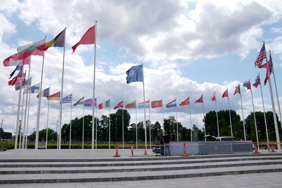 FILE - Two men do construction work around the flags at NATO headquarters in Brussels, Thursday, July 6, 2023. As the Russian invasion of Ukraine continues with no end in sight, NATO's much-celebrated unity faces fresh strains when leaders gather for their annual summit this week in Vilnius, Lithuania. Disagreements have been stacking up over admitting Sweden as NATO's 32nd member, boosting military spending and finding a new secretary general. (AP Photo/Virginia Mayo, File)