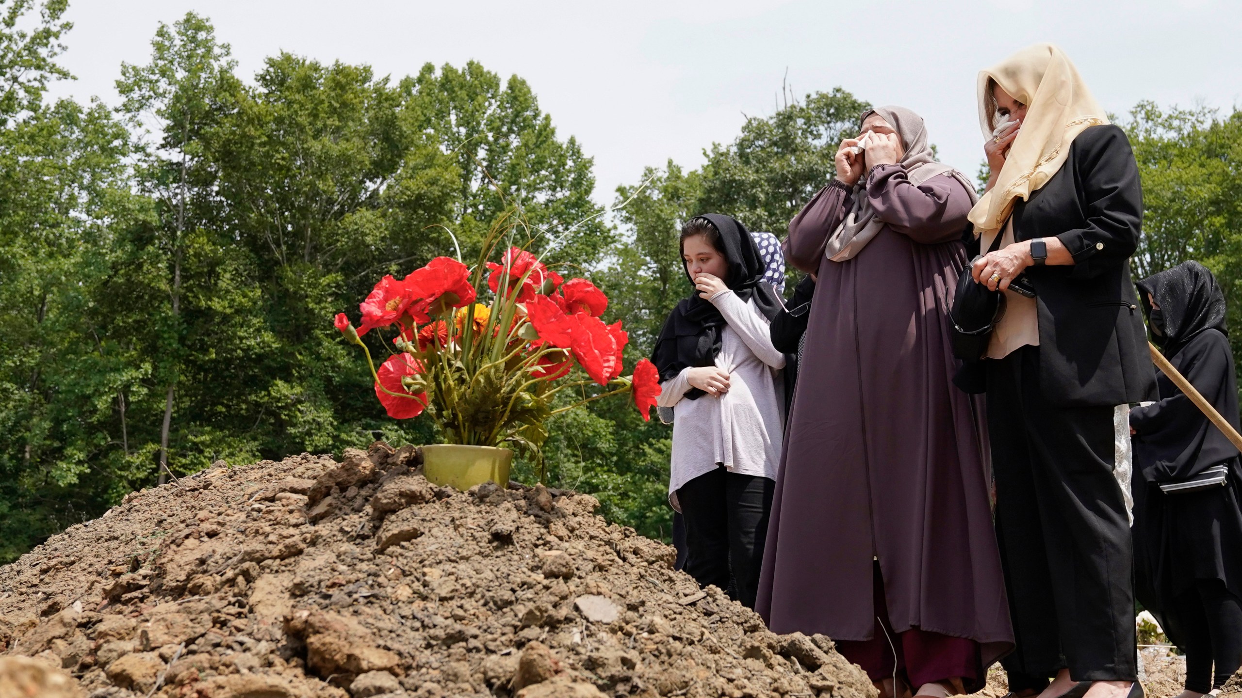 Muzhgan Ahmad Yar, center, Nasrat Ahmad Yar's wife cries at her husband's grave during his funeral service at the All Muslim Association of America cemetery on Saturday, July 8, 2023, in Fredericksburg, Va. Ahmad Yar, an Afghan immigrant who worked as an interpreter for the U.S. military in Afghanistan, was shot and killed on Monday, July 3, while working as a ride-share driver in Washington. (AP Photo/Mariam Zuhaib)