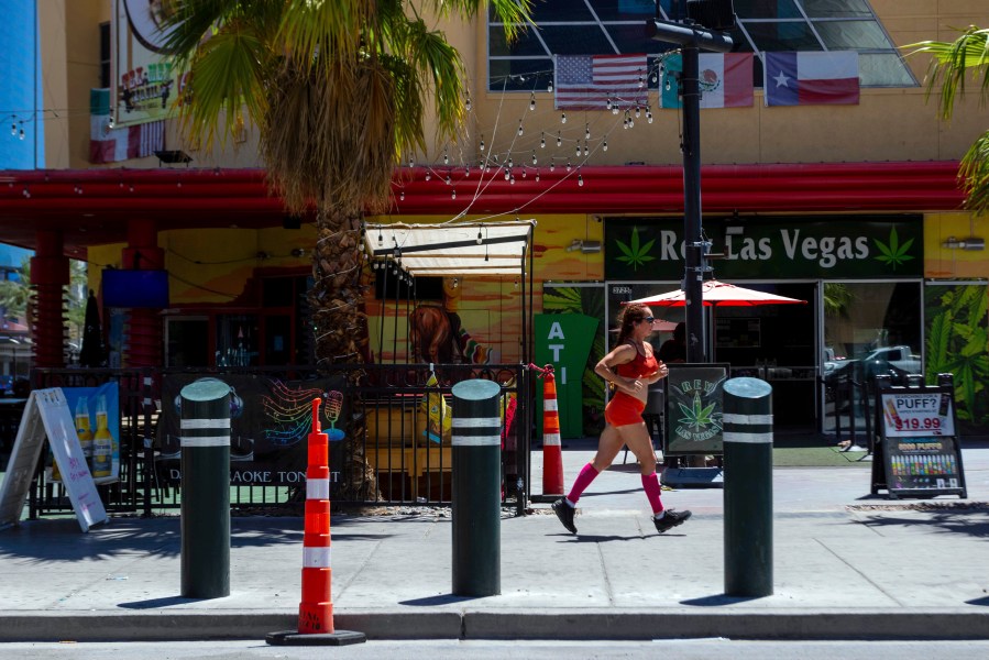 A person jogs on the Las Vegas strip during a heat advisory, Friday, July 14, 2023 in Las Vegas. Nearly a third of Americans were under extreme heat advisories, watches and warnings Friday, including in Las Vegas as a high pressure dome moves west from Texas. (AP Photo/Ty O'Neil)