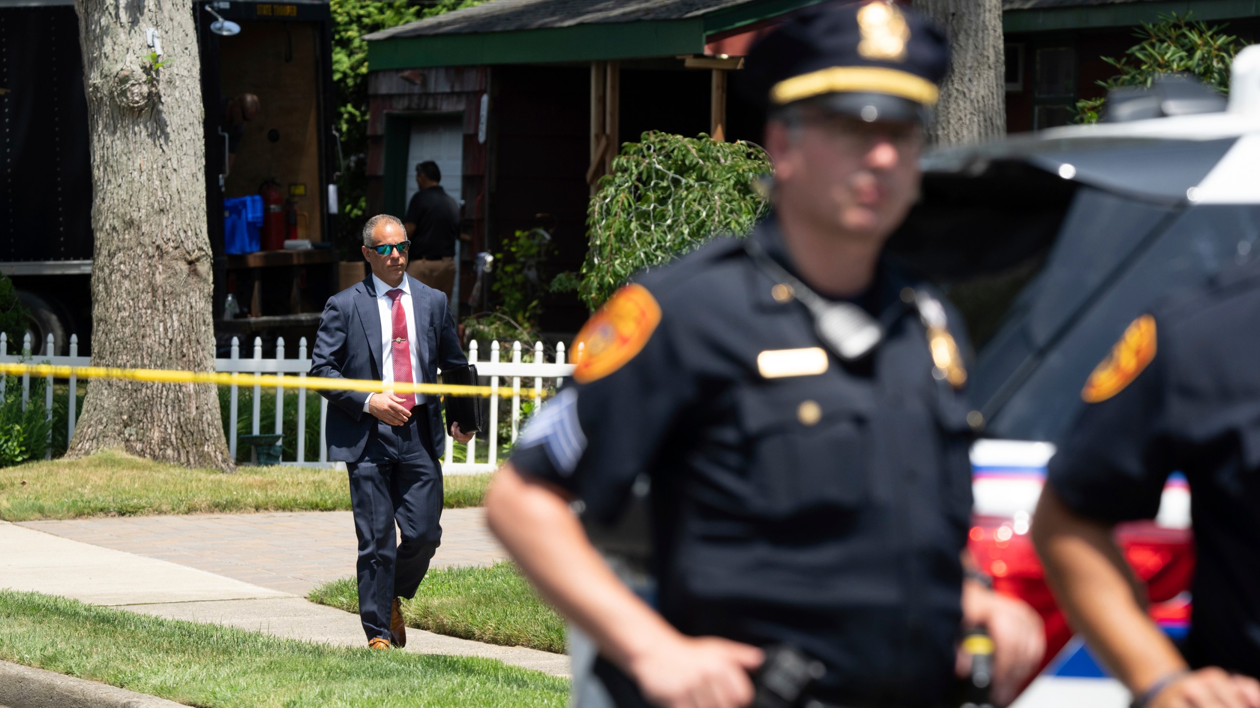 Police officers stand guard as law enforcement searches the home of Rex Heuermann, Saturday, July 15, 2023, in Massapequa Park, N.Y. Heuermann, a Long Island architect, was charged Friday, July 14, with murder in the deaths of three of the 11 victims in a long-unsolved string of killings known as the Gilgo Beach murders. (AP Photo/Jeenah Moon)