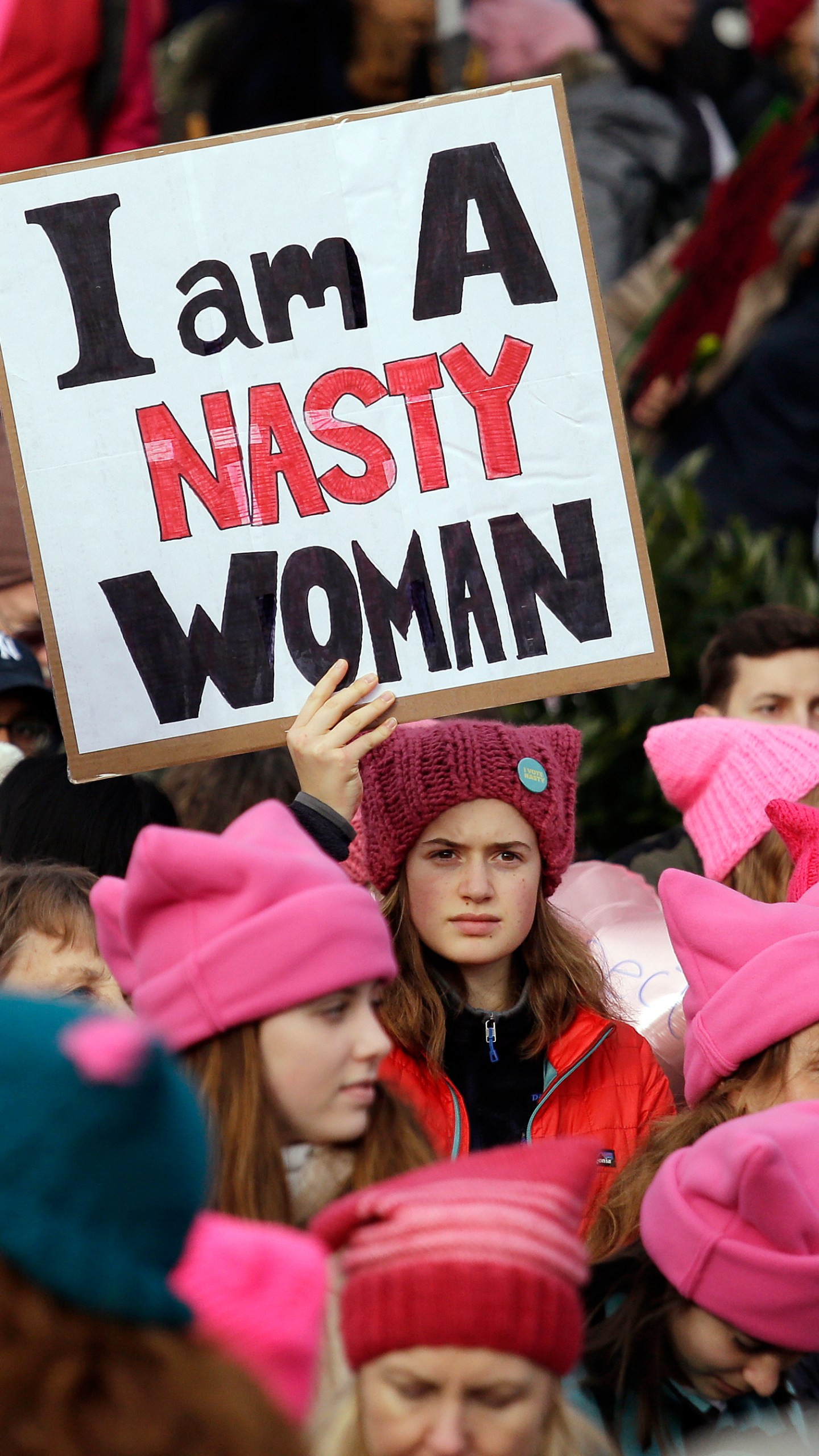 FILE - A woman holds a sign amidst a sea of pink caps before a women's march of more than 100,000, Jan. 21, 2017, in Seattle. Women across the Pacific Northwest marched in solidarity with the Women's March on Washington to send a message in support of women's rights and other causes. Pink's symbiotic influence — providing texture and receiving a boost from a cultural force — was evident in 2017 at the Women's March on Washington, where demonstrators donned loudly pink “pussy hats.”v(AP Photo/Elaine Thompson, File)