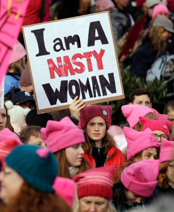 FILE - A woman holds a sign amidst a sea of pink caps before a women's march of more than 100,000, Jan. 21, 2017, in Seattle. Women across the Pacific Northwest marched in solidarity with the Women's March on Washington to send a message in support of women's rights and other causes. Pink's symbiotic influence — providing texture and receiving a boost from a cultural force — was evident in 2017 at the Women's March on Washington, where demonstrators donned loudly pink “pussy hats.”v(AP Photo/Elaine Thompson, File)