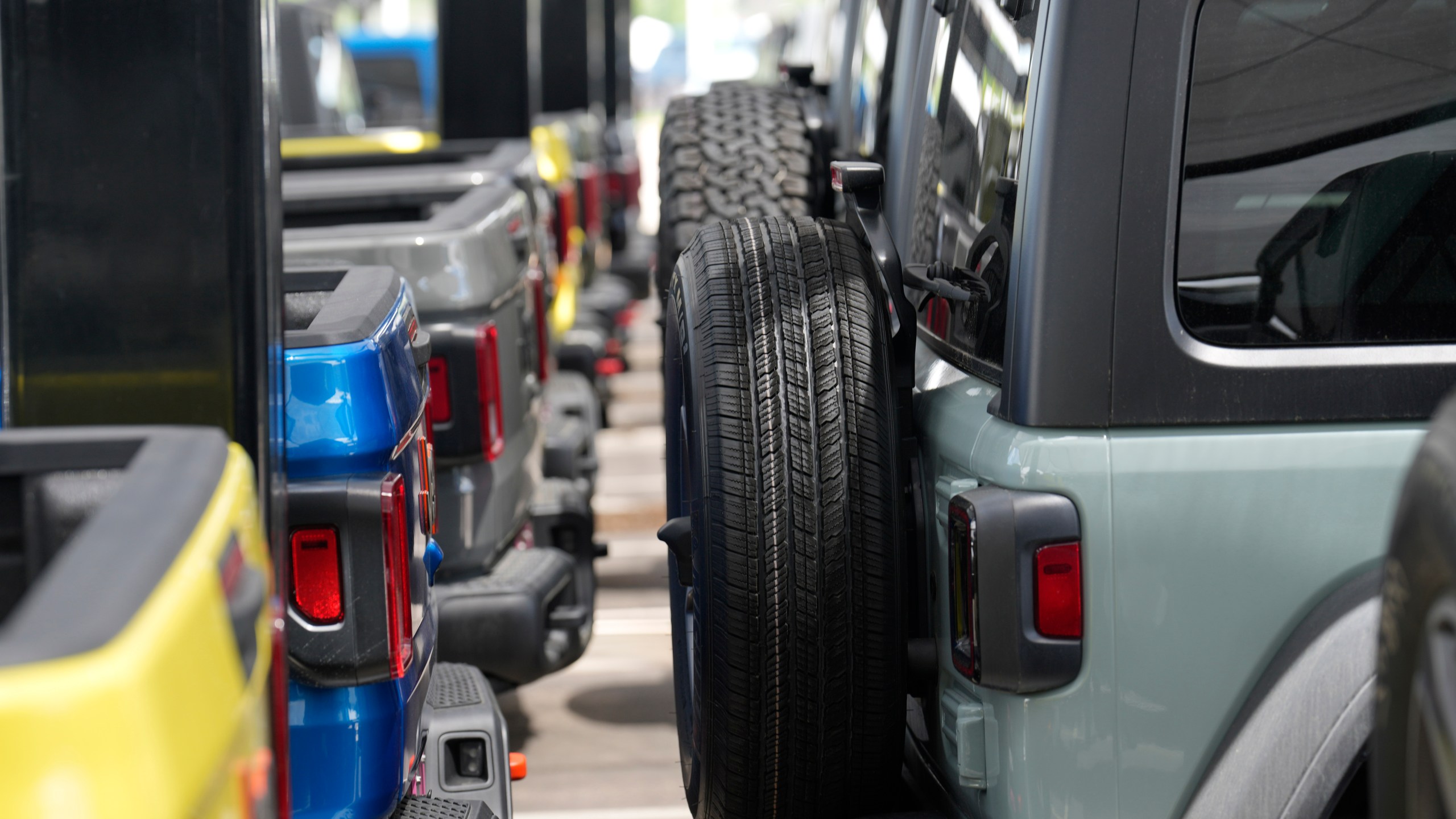 Unsold 2023 Gladiator pickup trucks, left, sit on display with Wrangler sports-utility vehicles at a Jeep dealership Sunday, June 18, 2023, in Englewood, Colo. On Tuesday, the Conference Board reports on U.S. consumer confidence for July. (AP Photo/David Zalubowski)