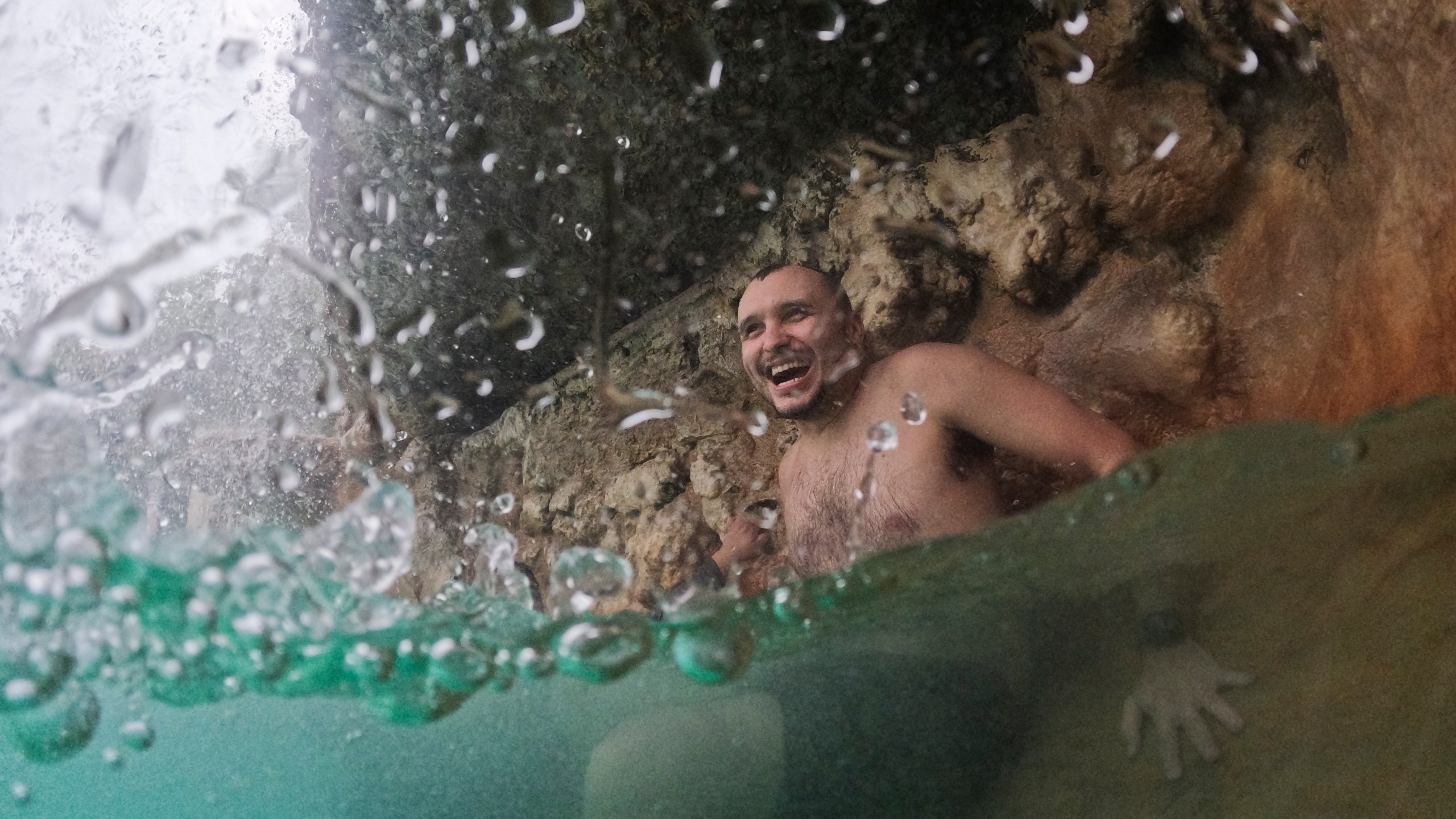 FILE - A young man cools off under a waterfall on a cloudy day with temperatures in the high 80s and intermittent rain storms, during a respite from an ongoing heat wave, at the aquifer-fed Venetian Pool in Coral Gables, Fla., July 27, 2023. Nearly 60% of the U.S. population, are under a heat advisory or flood warning or watch as the high temperatures spread and new areas are told to expect severe storms. (AP Photo/Rebecca Blackwell, File)