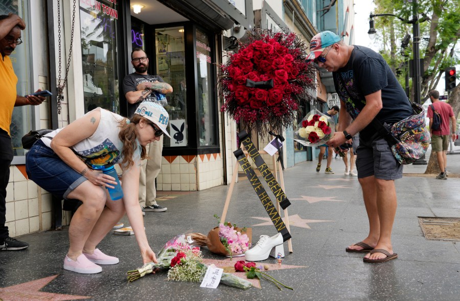 Sandy Neads, left, and James Owens lay flowers down on the star of Pee-wee Herman on the Hollywood Walk of Fame, Monday, July 31, 2023, in Los Angeles. Paul Reubens, the actor and comedian who created the Pee-wee Herman character, died Sunday night after a six-year struggle with cancer. (AP Photo/Chris Pizzello)