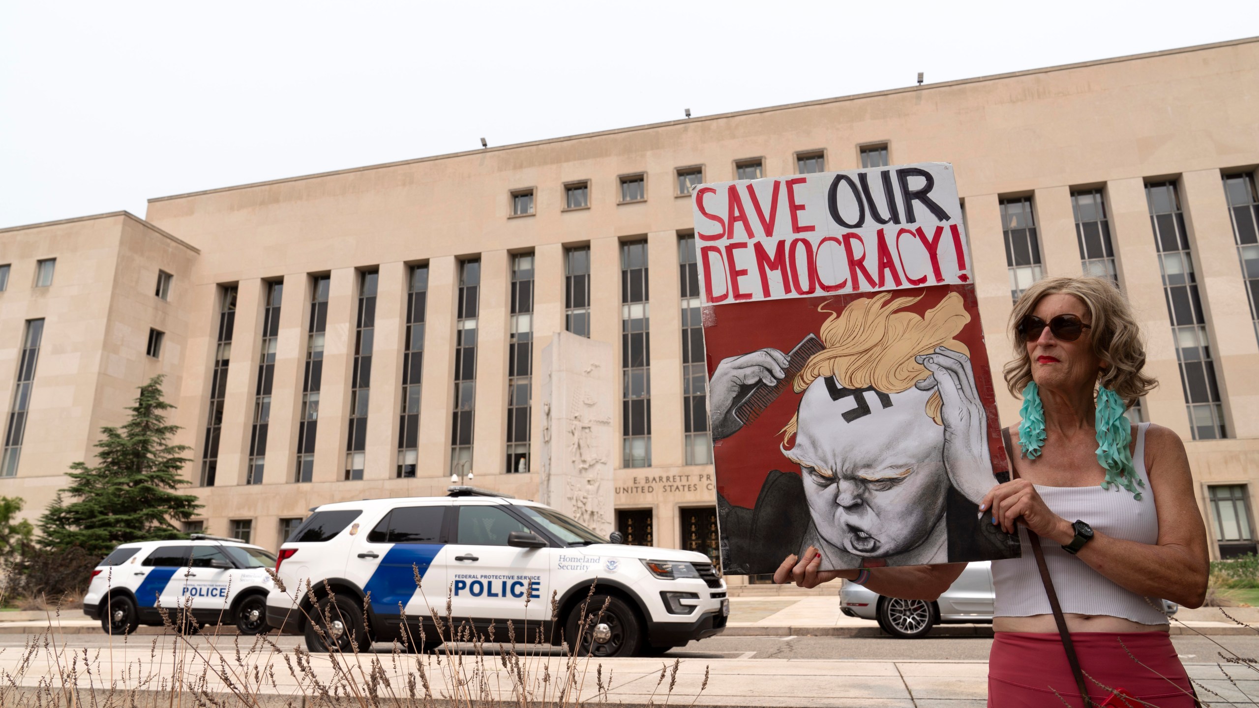 Nicky Sundt holds a banner outside the Federal District Court, Tuesday, Aug. 1, 2023 in Washington, where a grand jury has been meeting in the probe led by special counsel Jack Smith into former President Donald Trump. (AP Photo/Jose Luis Magana)