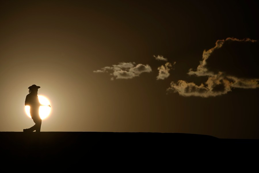 FILE - A person walks along a trail as the sun sets, Sunday, July 16, 2023, in Death Valley National Park, Calif. Human-caused global warming made July hotter for four out of five people on Earth, according to a new report issued Wednesday, Aug. 2, 2023, by Climate Central. (AP Photo/John Locher, File)