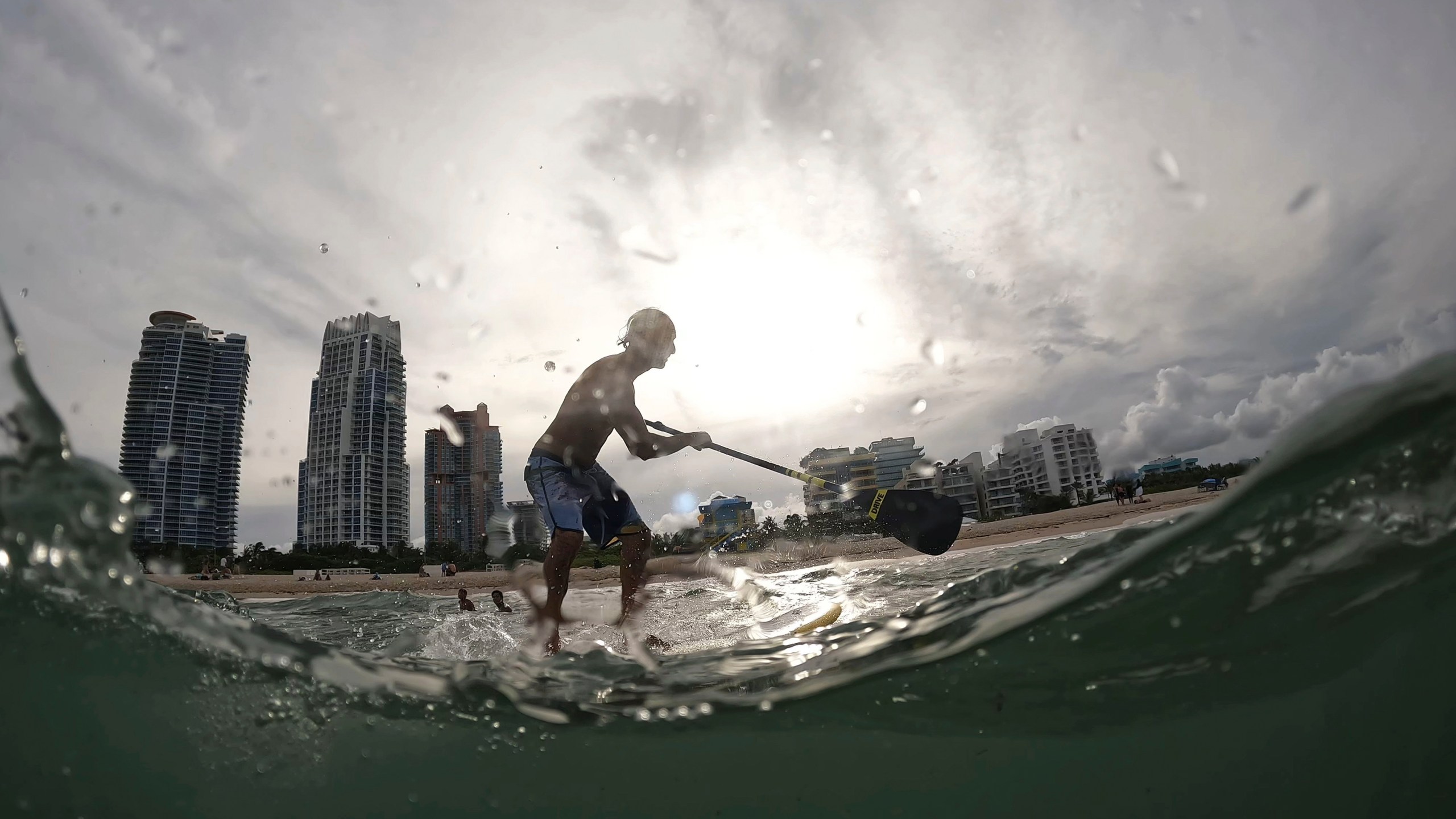 FILE - Graziano La Grasta, a local contractor and paddle board enthusiast, rides a small wave off South Beach, July 28, 2023, in Miami Beach, Fla. Across the U.S., many people are living through one of the most brutal summers of their lives and reckoning with the idea that climate change is only going to make matters worse in the coming decades. (AP Photo/Rebecca Blackwell, File)