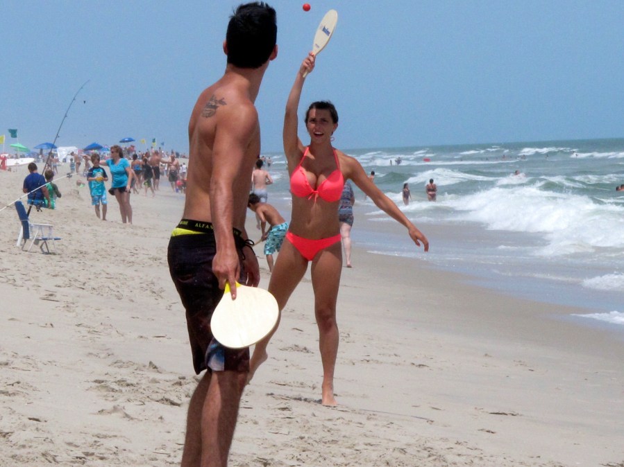 Beachgoers play paddle ball on the beach in Ship Bottom, N.J. on June 30, 2014. On Aug. 4, 2023, a German wind power company and a New York utility applied for permission to build a wind farm 37 miles off the coast of Long Beach Island, far enough out to sea that it could not be seen from the beach. (AP Photo/Wayne Parry)