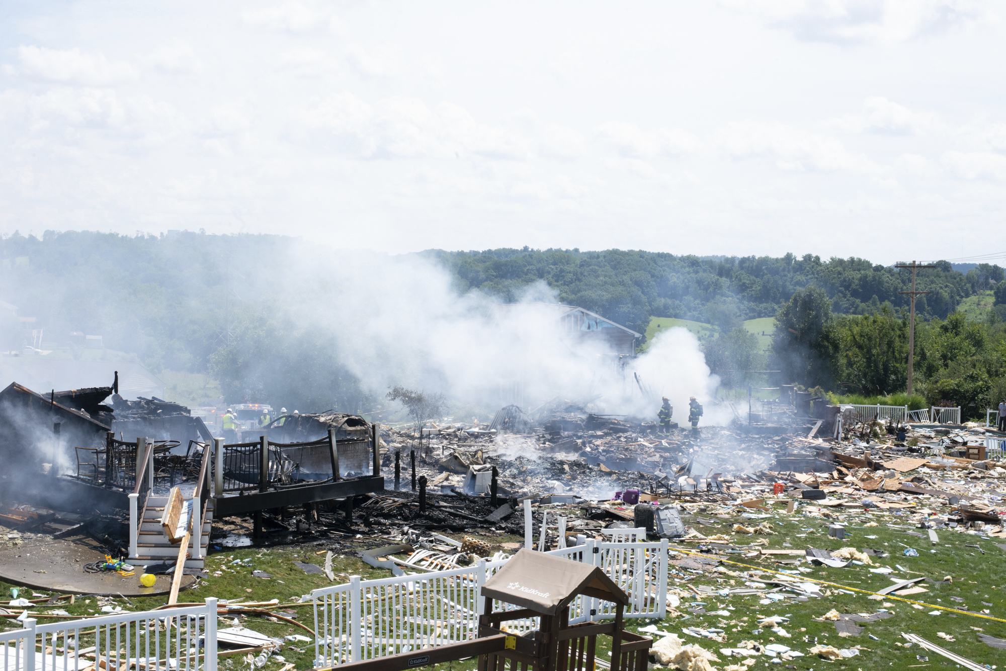 Two firefighters stand on the debris around the smoldering wreckage of the the three houses that exploded near Rustic Ridge Drive and Brookside Drive in Plum, Pa., on Saturday, Aug. 12, 2023. (Samuel Long/Pittsburgh Post-Gazette via AP)