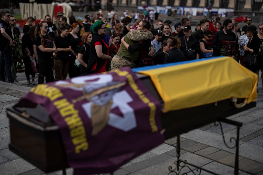 Friends of Daria Filipova, 34, hug each other at her funeral ceremony in Kyiv, Ukraine, Saturday, Aug. 12, 2023. Filipova was a medic in the Ukrainian army and died in an attack in the Donetsk region. (AP Photo/Bram Janssen)