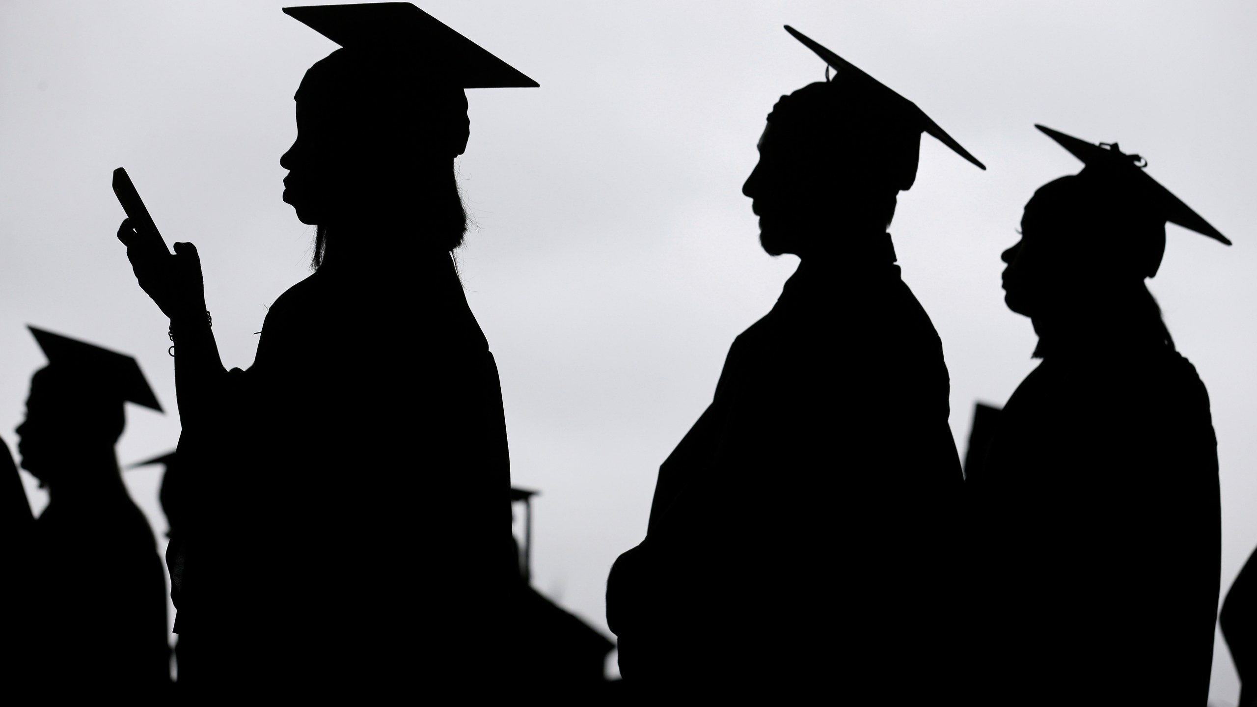 FILE - New graduates line up before the start of a community college commencement in East Rutherford, N.J., May 17, 2018. This summer, millions of Americans with student loans will be able to apply for a new repayment plan that offers some of the most lenient terms ever. Interest won’t pile up as long as borrowers make regular payments. Millions of people will have payments of $0. And starting in 2024, undergraduate loan payments will be reduced by half. (AP Photo/Seth Wenig, File)