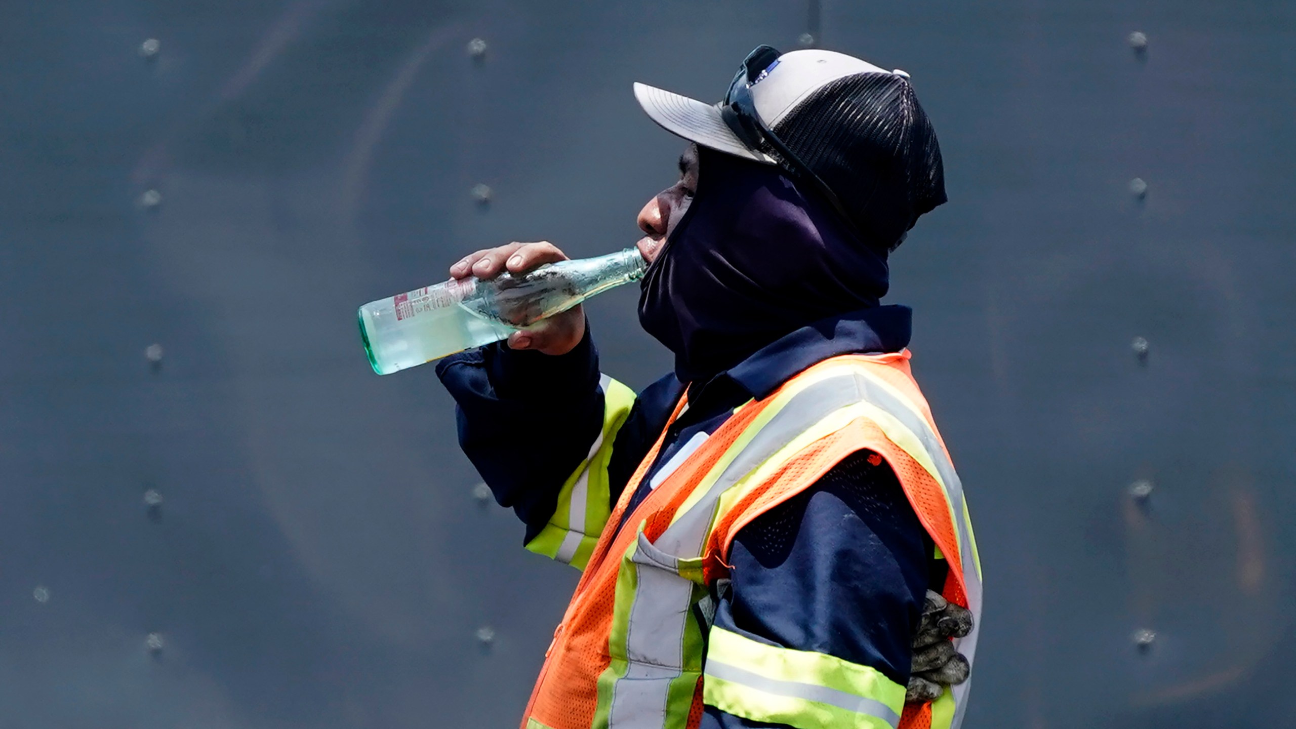 FILE - Standing in the mid-afternoon heat, a worker takes a break to drink during a parking lot asphalt resurfacing job in Richardson, Texas, June 20, 2023. While unrelenting heat set in across Texas this summer, opponents of a sweeping new law targeting local regulations took to the airwaves and internet with an alarming message: outdoor workers would be banned from taking water breaks. Workers would die, experts and advocates said, with high temperatures topping 100 degrees Fahrenheit (38 degrees Celsius) and staying there for much of the past two months. (AP Photo/LM Otero, File)