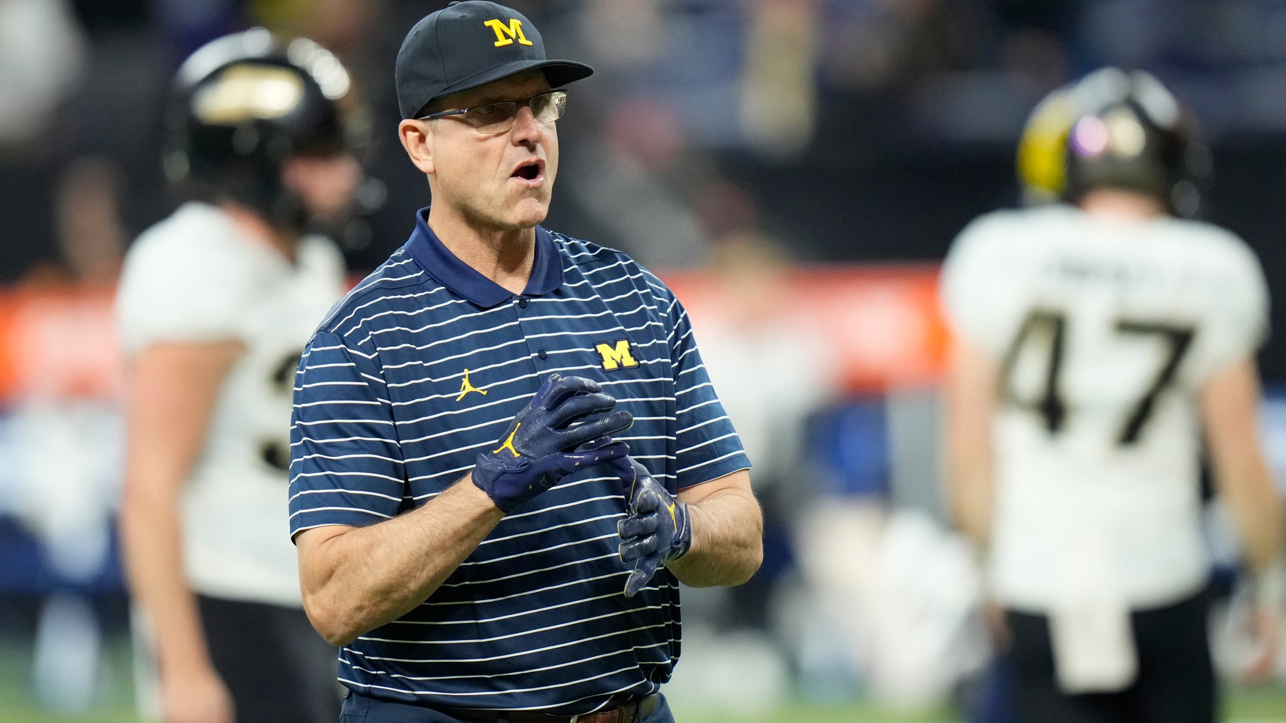 FILE - Michigan head coach Jim Harbaugh watches before the start of the Big Ten championship NCAA college football game against Purdue, Saturday, Dec. 3, 2022, in Indianapolis. Michigan coach Jim Harbaugh has informed his team and staff that he will serve a three-game suspension to start this season as part of the school’s self-imposed penalties for NCAA infractions, two people familiar with the situation told The Associated Press on Monday, Aug. 21, 2023. (AP Photo/AJ Mast, File)