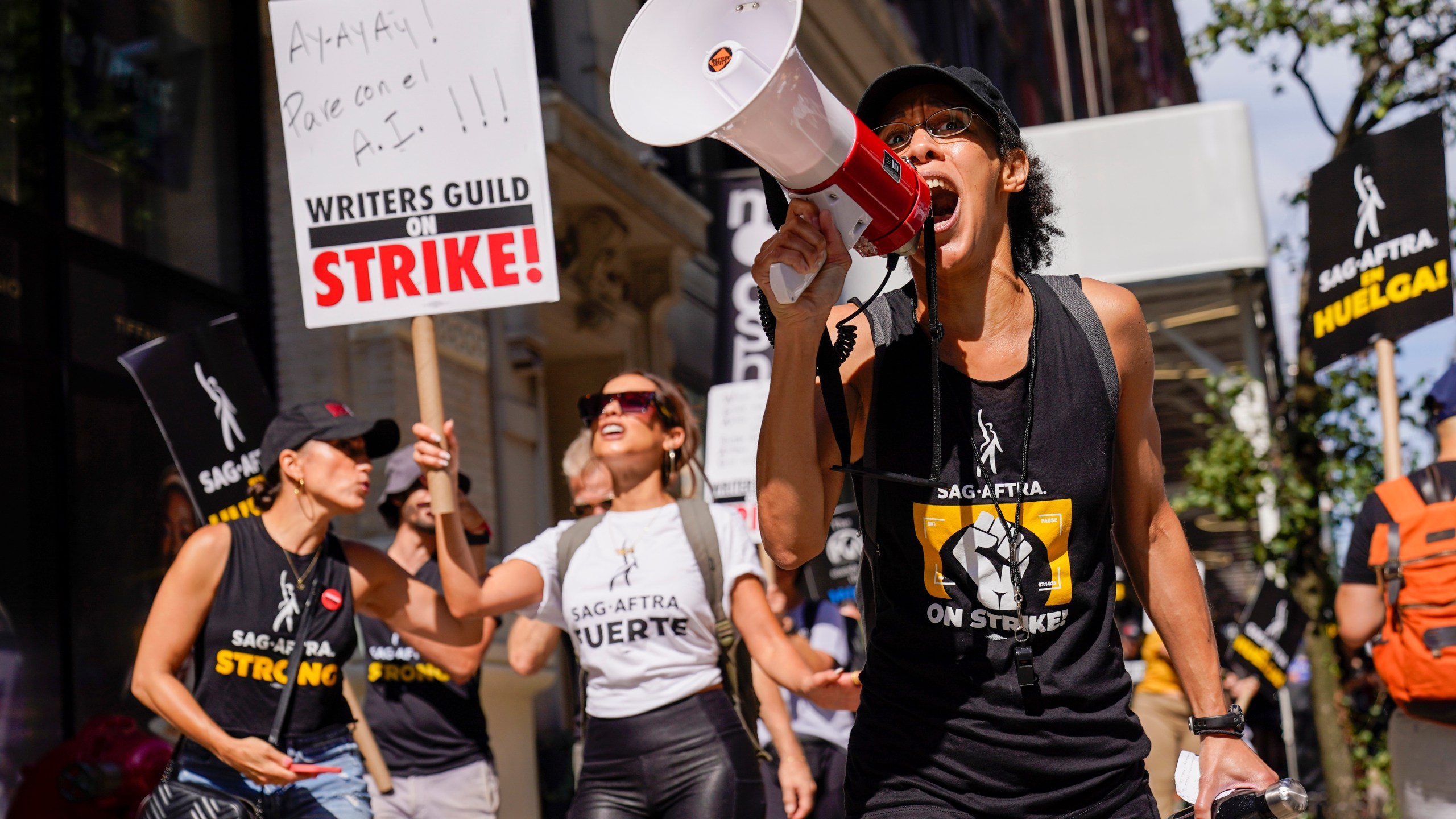 A strike captain, right, leads the chants as strikers walk a picket line outside Warner Bros., Discovery, and Netflix offices in Manhattan, Friday, Aug. 18, 2023. The WGA and SAG-AFTRA held a joint Latine Picket, presented by the WGAE Latine Writers Salon, the WGAW Latinx Writers Committee, and the SAG-AFTRA National Latino Committee. (AP Photo/Mary Altaffer)