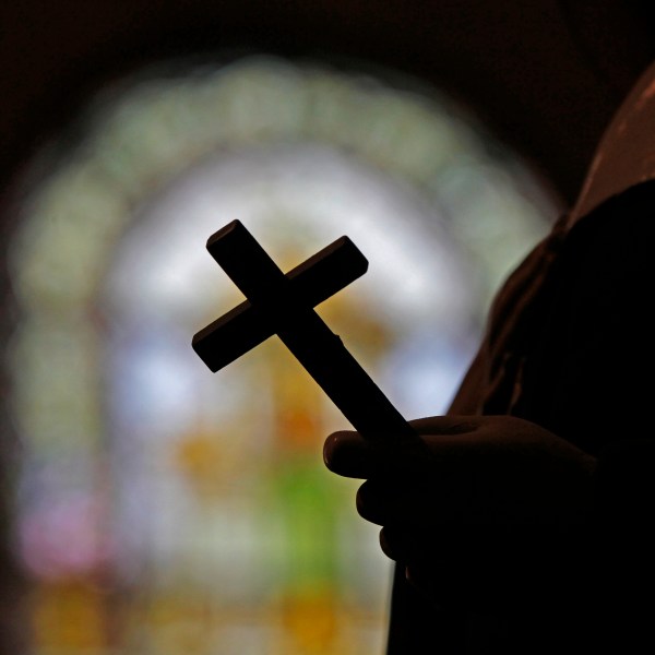 FILE - This Dec. 1, 2012 file photo shows a silhouette of a crucifix and a stained glass window inside a Catholic Church in New Orleans. On Thursday, Sept. 7, 2023, a Louisiana state grand jury charged a now-91-year-old disgraced priest, Lawrence Hecker, with sexually assaulting a teenage boy in 1975, an extraordinary prosecution that could shed new light on what Roman Catholic Church leaders knew about a child sex abuse crisis that persisted for decades and claimed hundreds of victims. (AP Photo/Gerald Herbert, File)