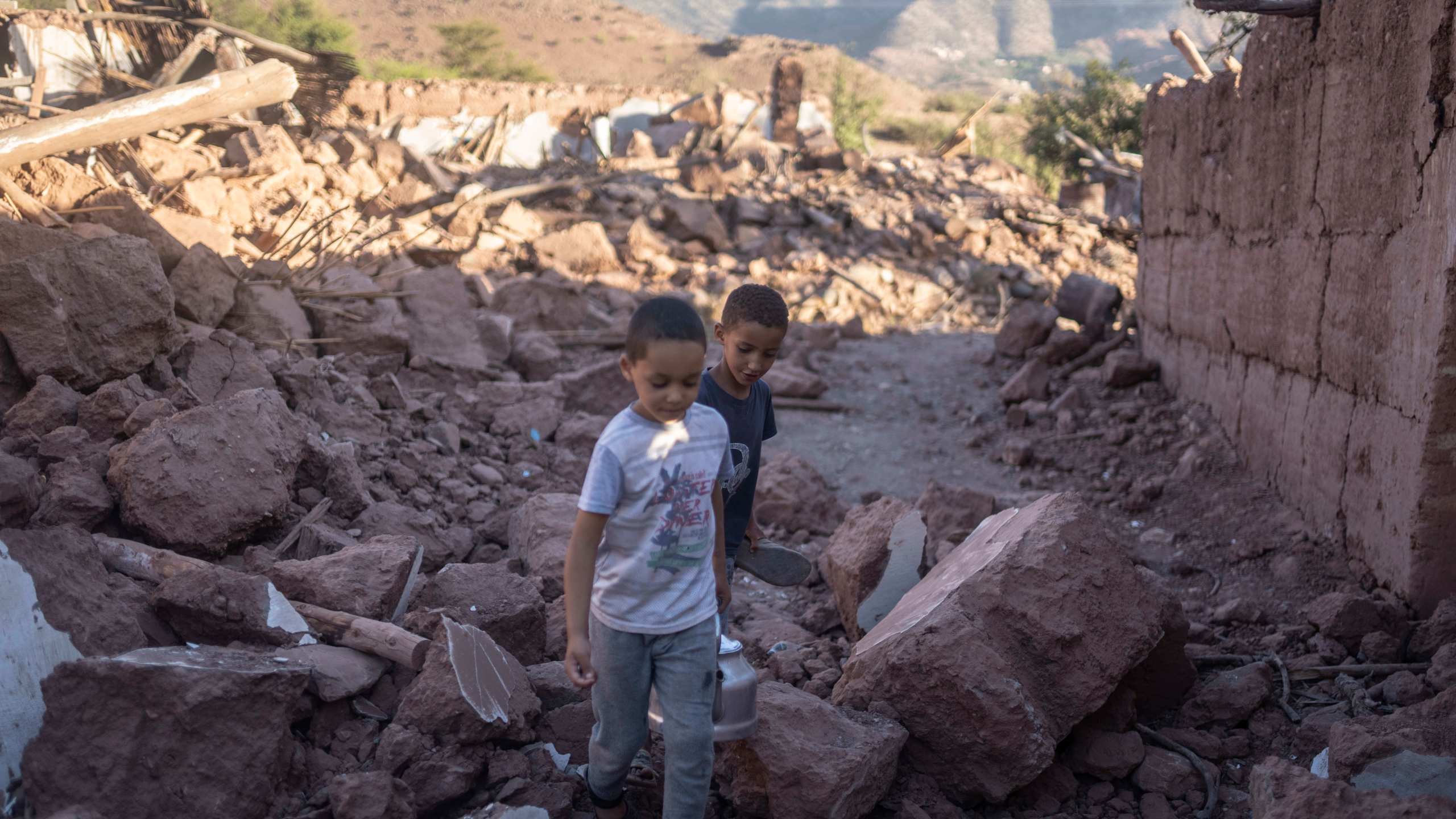 Moroccan boys, Rayan and Ali walk amidst the rubble of their home which was damaged by the earthquake, in Ijjoukak village, near Marrakech, Morocco, Saturday, Sept. 9, 2023. A rare, powerful earthquake struck Morocco, sending people racing from their beds into the streets and toppling buildings in mountainous villages and ancient cities not built to withstand such force. (AP Photo/Mosa'ab Elshamy)