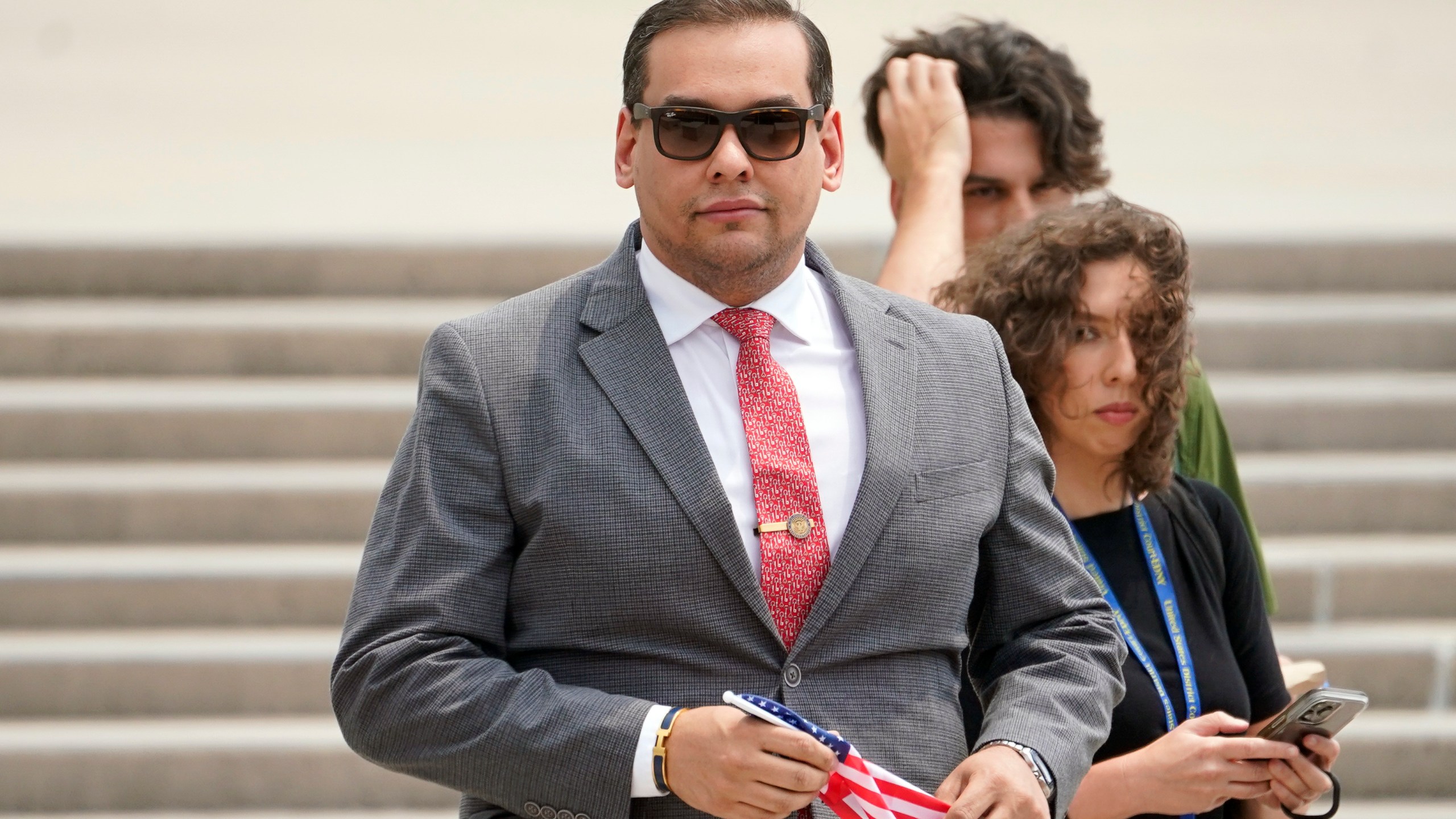 FILE - U.S. Rep. George Santos, R-N.Y., holds a miniature American flag that was presented to him as he departs federal court, Friday, June 30, 2023, in Central Islip, N.Y. Sam Miele, a former political fundraiser for Santos, was arrested Wednesday, Aug. 16, on federal charges of wire fraud and aggravated identity theft as part of an alleged scheme to trick donors into giving money to Santos under a false name. (AP Photo/John Minchillo, File)