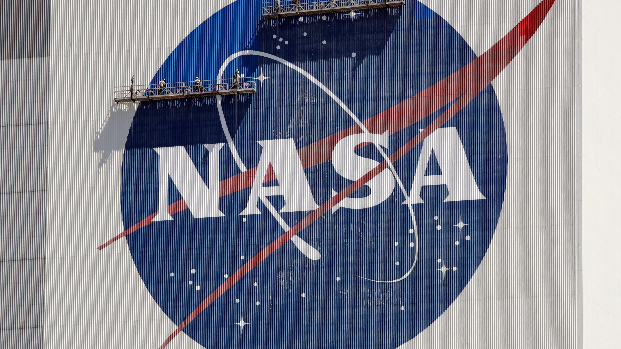 FILE - Workers on scaffolding repaint the NASA logo near the top of the Vehicle Assembly Building at the Kennedy Space Center in Cape Canaveral, Fla., Wednesday, May 20, 2020. After a yearlong study into UFOs, NASA is releasing a report Thursday, Sept. 14, 2023, on what it needs to better understand unidentified flying objects from a scientific point of view. (AP Photo/John Raoux, File)