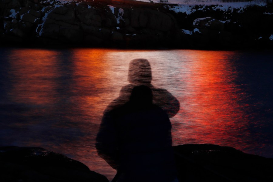 FILE - In this photo made with a long exposure, a man is silhouetted against lights reflected in the waters off Cape Neddick in Maine on Dec. 11, 2017. A study published Thursday, Sept. 14, 2023, in the journal Nature Medicine has found that the psychedelic drug MDMA, combined with talk therapy, can reduce symptoms of post-traumatic stress disorder. (AP Photo/Robert F. Bukaty, File)