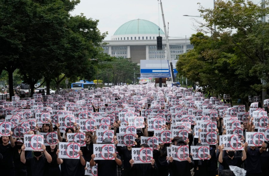 Teachers hold up their banners during a rally to demand the better protection of their rights near the National Assembly in Seoul, South Korea, Saturday, Sept. 16, 2023. Following the suicide of an elementary school teacher in July, teachers across South Korea have been pushing for improved systems to protect teachers from widespread malicious complaints from parents. The signs read "Pass (the teacher rights restoration bills) in September parliament session." (AP Photo/Ahn Young-joon).