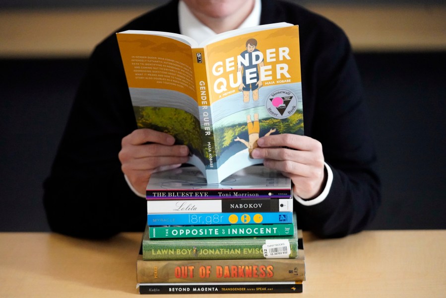 FILE - Amanda Darrow, director of youth, family and education programs at the Utah Pride Center, poses with books that have been the subject of complaints from parents on Dec. 16, 2021, in Salt Lake City. The nationwide surge in book bannings continues. The American Library Association reported Wednesday, Sept. 20, 2023, that challenges to books in schools and public libraries will likely reach record highs in 2023, topping what had been a record pace in 2022. (AP Photo/Rick Bowmer, File)