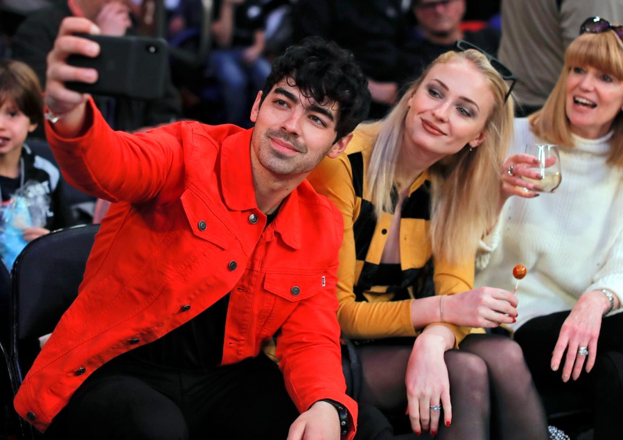 FILE Musician Joe Jonas, left, takes a selfie with actress Sophie Turner during a break in play of an NBA basketball game between the New York Knicks and the Sacramento Kings, Saturday, March 9, 2019, in New York. Turner sued her estranged pop star husband Jonas on Thursday, Sept. 21, 2023, to force him to turn over the passports of the couple's two young daughters so she can take them to England. (AP Photo/Julie Jacobson, File)