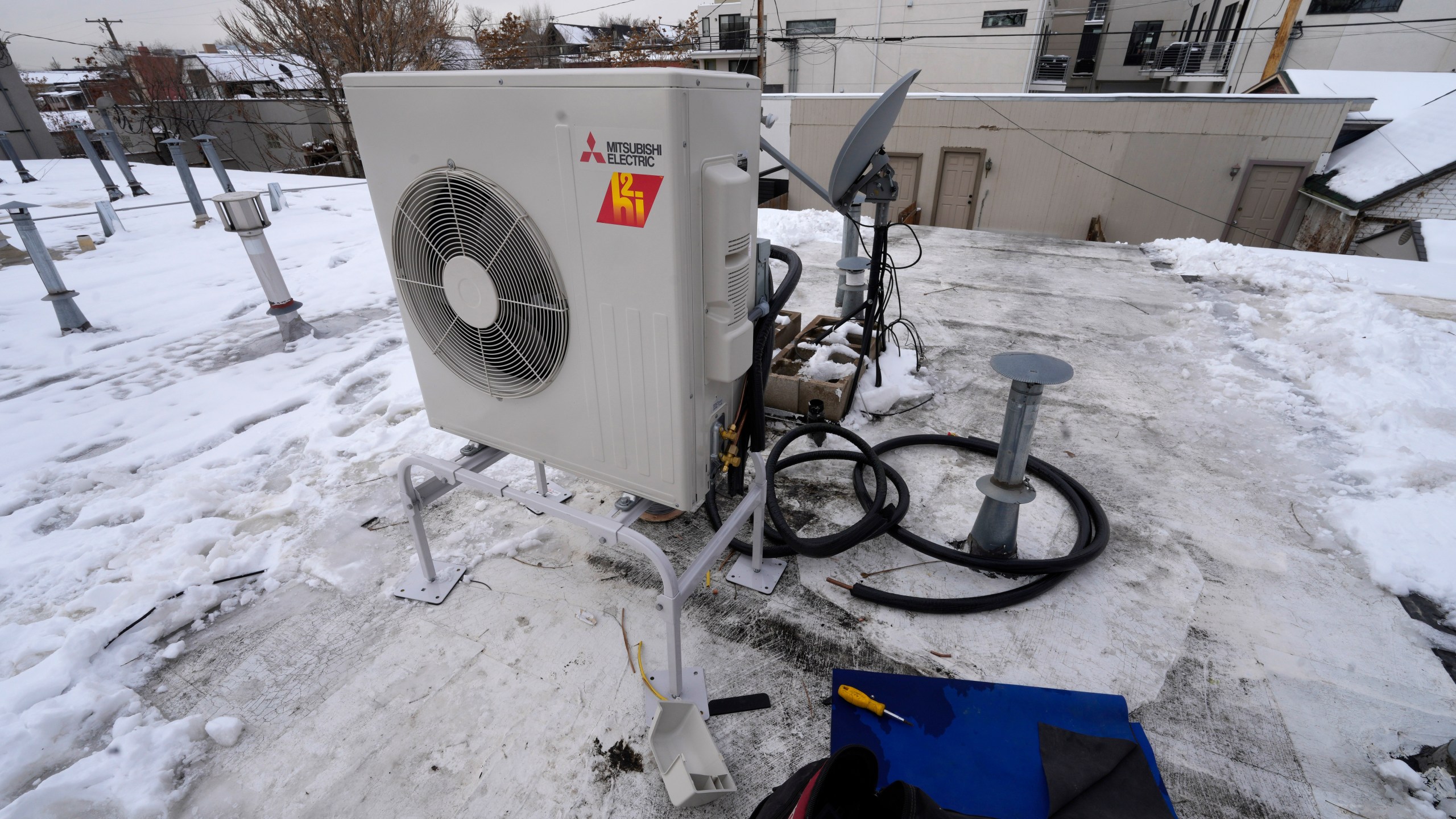 FILE - A condenser sits on the roof during the installation of a heat pump on Jan. 20, 2023, in Denver. A bipartisan coalition of about 25 governors and the Biden administration are set to announce a pledge Thursday, Sept. 21, 2023, to quadruple the number of heat pumps in U.S. homes by 2030. (AP Photo/David Zalubowski, File)